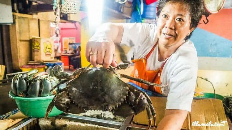 Filipina fish vendor holding up crab.