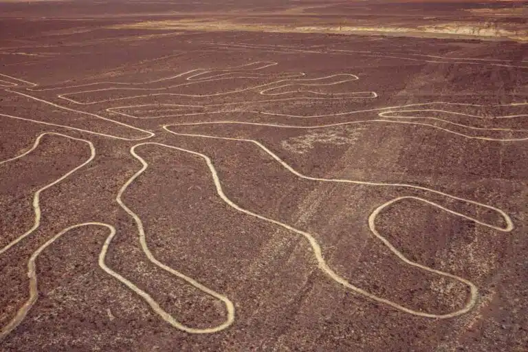 A Long Line Drawn On A Dirt Field With Nazca Lines In The Background